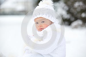 Cute little toddler boy, playing outdoors with snow on a winter day