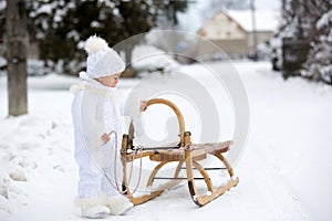 Cute little toddler boy, playing outdoors with snow on a winter day