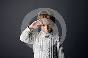 Roztomilý malý batole chlapec zobrazené ahoj gesto v jazyk na šedá obraz 