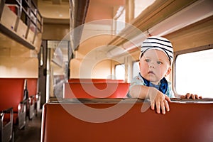 Cute little toddler boy sitting inside the train. Child traveling by railway. young traveler. Vacations. Indoors