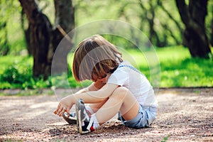 cute little toddler child boy playing with dirt and sitting on the ground