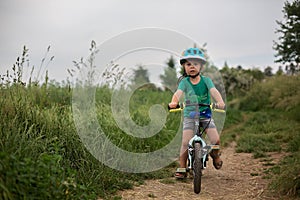Cute little toddler child, riding a bike in the park photo
