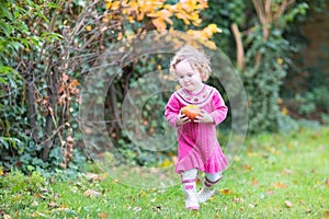 Cute little toddler girl with apple in autumn garden