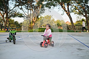 Cute little toddler girl child learning to ride first balance bike, children cycling at the park