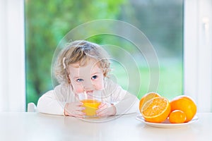 Cute little toddler girl drinking orange juice