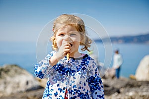 Cute little toddler girl eating ice cream in cone on family vacations. Happy healthy baby child with icecream waffle