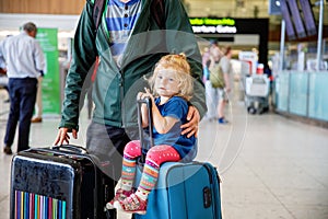 Cute little toddler girl and father at the airport. Happy family traveling by plane, making vacations. Young dad and baby daughter