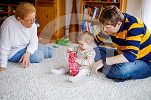 Cute little toddler girl, father and grandmother playing together. baby child, dad and and senior retired woman