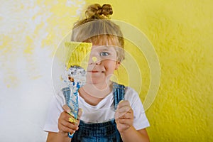 Cute little toddler girl painting the wall with yellow color in new house. Family repair apartment home. Happy child