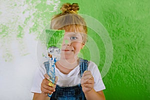 Cute little toddler girl painting the wall with yellow color in new house. Family repair apartment home. Happy child