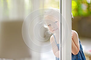 Cute little toddler girl peeking into a window