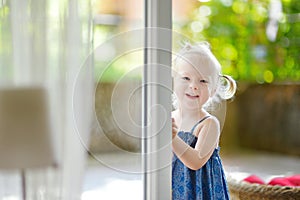 Cute little toddler girl peeking into a window