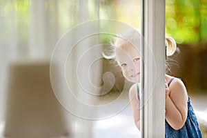 Cute little toddler girl peeking into a window
