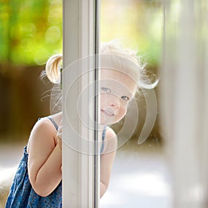 Cute little toddler girl peeking into a window