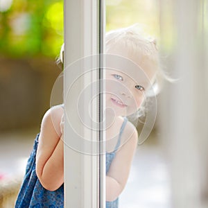 Cute little toddler girl peeking into a window