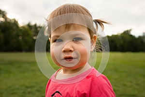 Cute Little toddler girl in pink dress playing in park in front of green grass