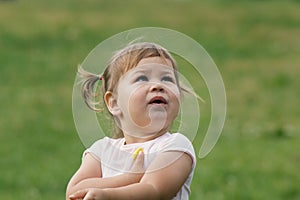 Cute Little toddler girl playing in park in front of green grass