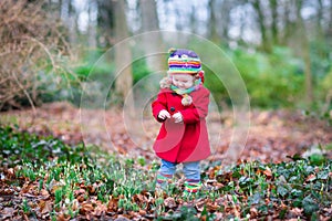 Cute little toddler girl in red coat in autumn park