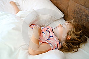 Cute little toddler girl sleeping in bed. Adorable baby child dreaming, healthy sleep of children by day. Deep sleeping