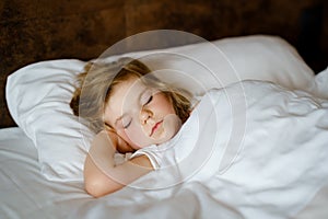 Cute little toddler girl sleeping in bed. Adorable baby child dreaming, healthy sleep of children by day. Deep sleeping