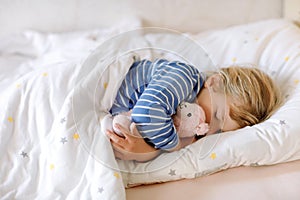 Cute little toddler girl sleeping in bed with favourite soft plush toy lama. Adorable baby child dreaming, healthy sleep