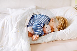 Cute little toddler girl sleeping in bed with favourite soft plush toy lama. Adorable baby child dreaming, healthy sleep