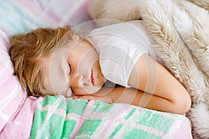 Cute little toddler girl sleeping in bed. Tired preschool child dreaming, healthy sleep of children by day.