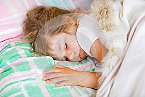 Cute little toddler girl sleeping in bed. Tired preschool child dreaming, healthy sleep of children by day.