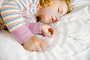 Cute little toddler girl sleeping in big bed of parents. Adorable baby child dreaming in hotel bed on family vacations