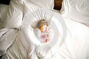 Cute little toddler girl sleeping in big bed of parents. Adorable baby child dreaming in hotel bed on family vacations