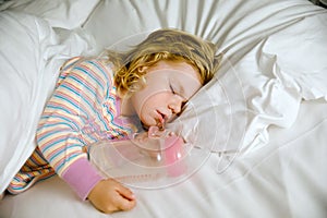 Cute little toddler girl sleeping in big bed of parents. Adorable baby child dreaming in hotel bed on family vacations