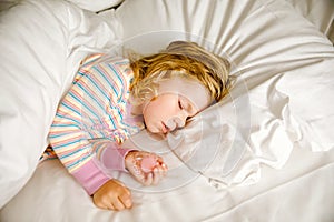 Cute little toddler girl sleeping in big bed of parents. Adorable baby child dreaming in hotel bed on family vacations