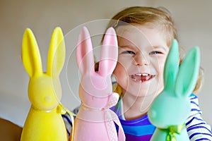 Cute little toddler girl with three colored pastel bunnies Happy baby child having fun with Easter decorations bunny in