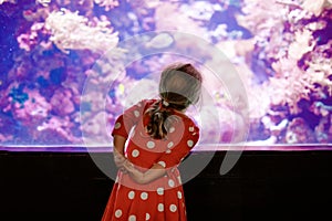 Cute little toddler girl visiting zoo aquarium. Happy baby child watching fishes and jellyfishes, corals. Fascinated