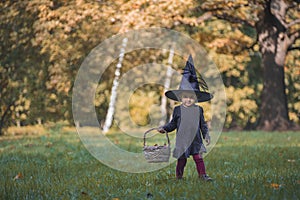 Cute little todler giirl witch in hallowem costume in fall forest