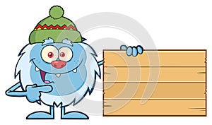 Cute Little Yeti Cartoon Mascot Character With Hat Pointing To A Wooden Blank Sign