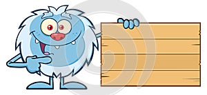 Cute Little Yeti Cartoon Mascot Character Pointing To A Wooden Blank Sign