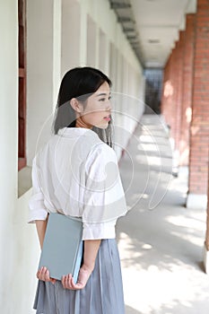 Cute lovely Asian Chinese pretty girl wear student suit in school in class enjoy free time smile and reading book