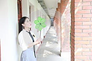 Cute lovely Asian Chinese pretty girl wear student suit in school in class play with green windmill