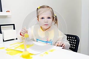 Cute lovely little girl painting with foam brush at home
