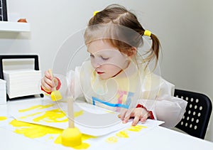 Cute lovely little girl painting with foam brush at home