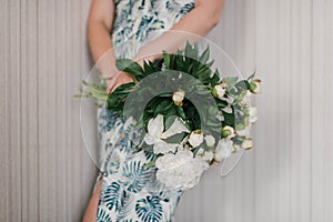 Cute and lovely peony flowers in women`s hands.. many layered petals. Bunch pale white peonies flowers light gray background