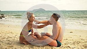 Cute loving couple each other having sun block. Woman to put sunscreen man. Young girl and guy using sun cream.