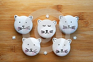 Cute macarons in a shape of cats on wooden board, small sugar snowflakes around, top view