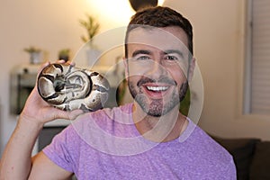Cute man holding exotic ball python