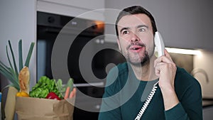 Cute man talking with corded telephone