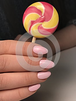 Cute manicured nails with lollipop in hand