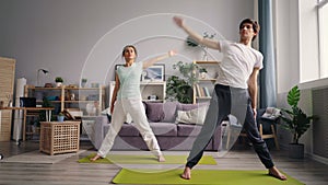 Cute married couple girl and guy training at home doing yoga indoors on mats