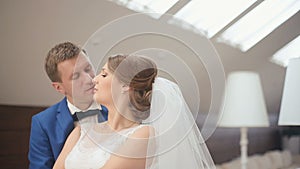 Cute married couple in the luxurious cafe. Close-up tender moment of groom kissing bride and softly smiling.