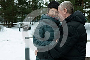 Cute mature couple experiencing love for each other while walking in the park in winter